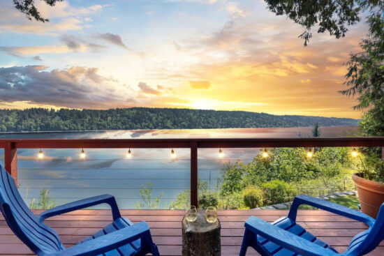Balcony overlooking the water at sunset with glasses of wine