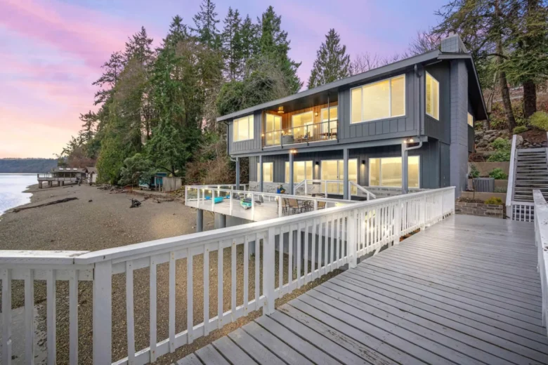 Home with a deck overlooking the beach and water at sunset