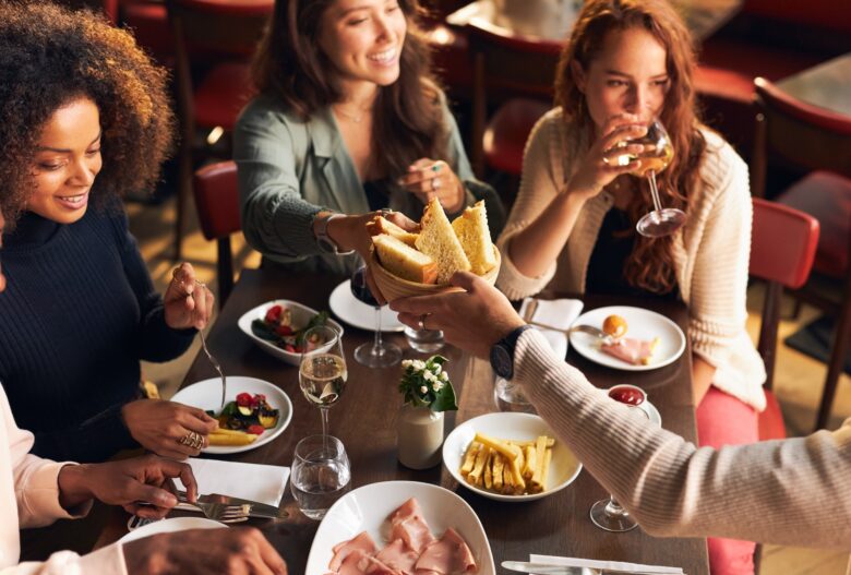 A group of friends enjoying food and drinks at a restaurant